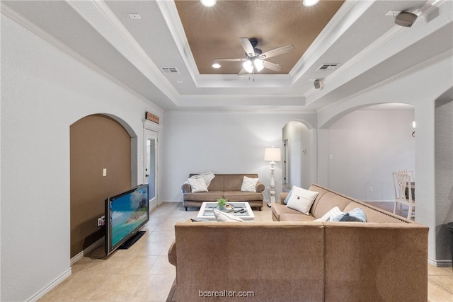 living room with ceiling fan, ornamental molding, light tile patterned floors, and a tray ceiling