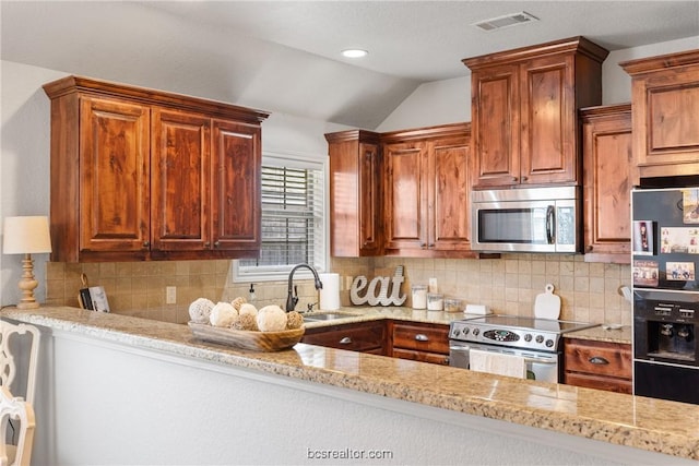 kitchen with light stone countertops, sink, backsplash, lofted ceiling, and appliances with stainless steel finishes