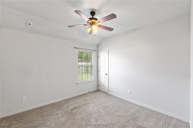 carpeted spare room with a textured ceiling, ceiling fan, and vaulted ceiling