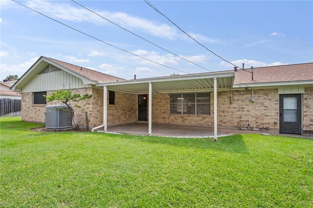 rear view of property with central air condition unit, a patio area, brick siding, and a yard