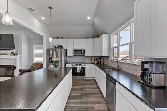 kitchen with dark countertops, visible vents, stainless steel appliances, and a sink