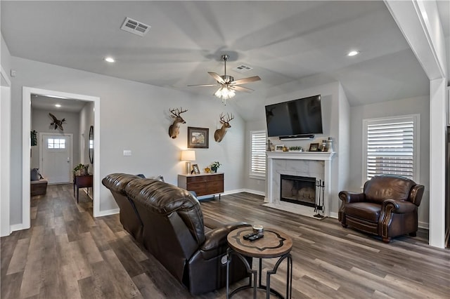 living area with visible vents, a fireplace, baseboards, and wood finished floors