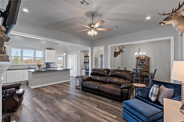 living area featuring recessed lighting, visible vents, dark wood-type flooring, and ceiling fan with notable chandelier