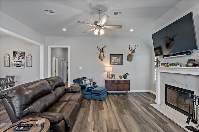 living area with a ceiling fan, a premium fireplace, visible vents, and wood finished floors