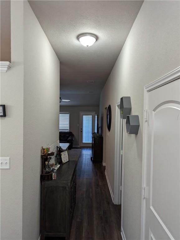 corridor with dark hardwood / wood-style floors and a textured ceiling