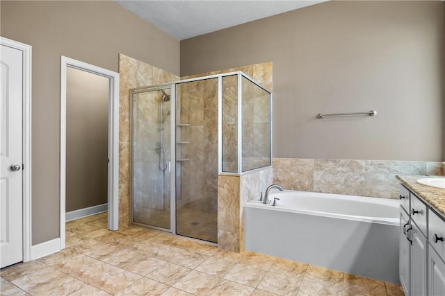 bathroom with a textured ceiling, vanity, and separate shower and tub