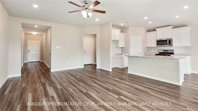 kitchen featuring light stone countertops, stainless steel appliances, white cabinetry, and a center island with sink