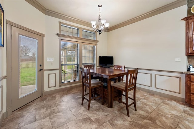 dining room featuring a decorative wall, wainscoting, crown molding, and an inviting chandelier