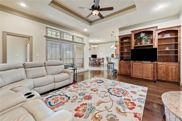 living room with a tray ceiling, dark wood-style floors, and crown molding