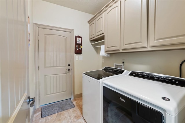 laundry room with cabinet space, light tile patterned floors, and washer and dryer