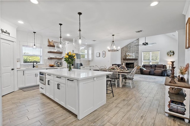 kitchen featuring pendant lighting, white cabinets, sink, tasteful backsplash, and a kitchen island