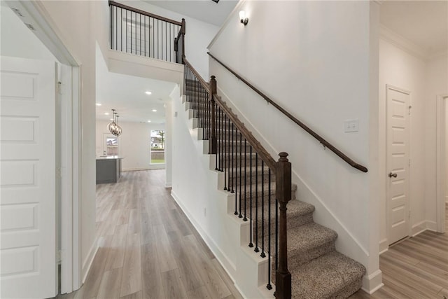 stairway with hardwood / wood-style flooring and crown molding