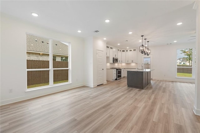 kitchen featuring white cabinets, pendant lighting, a center island, and light hardwood / wood-style floors