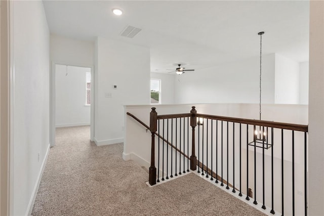 corridor featuring a notable chandelier and light colored carpet