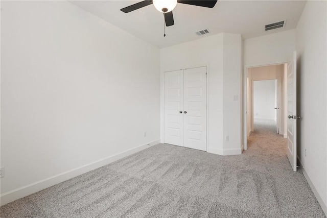 unfurnished bedroom featuring ceiling fan, a closet, and light carpet