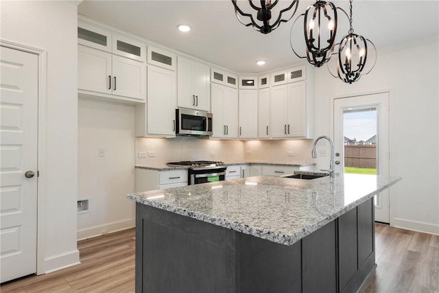 kitchen featuring white cabinets, stainless steel appliances, a kitchen island with sink, sink, and a chandelier