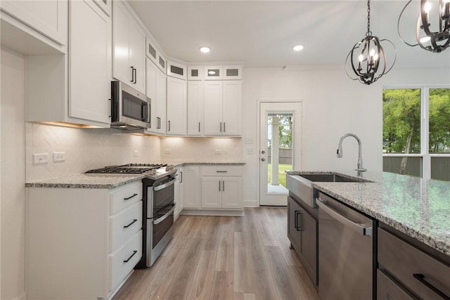 kitchen with a chandelier, white cabinetry, light stone countertops, and stainless steel appliances