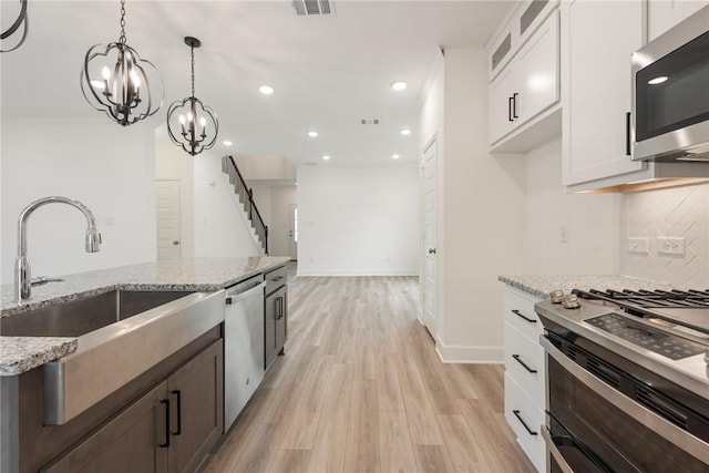 kitchen featuring backsplash, white cabinets, light stone countertops, light hardwood / wood-style floors, and stainless steel appliances