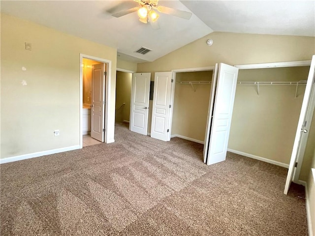 unfurnished bedroom with light carpet, two closets, lofted ceiling, and ceiling fan