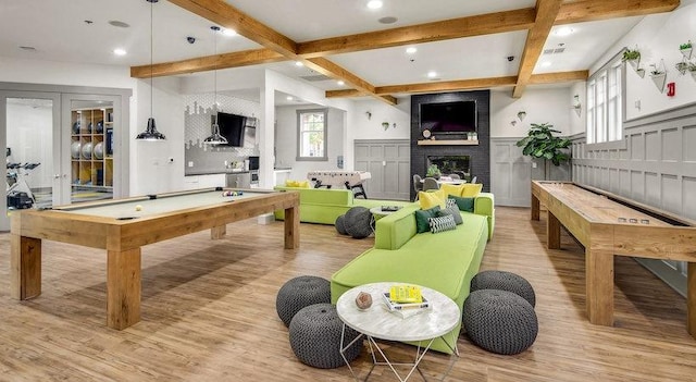 rec room with a fireplace, beamed ceiling, pool table, light wood-type flooring, and french doors