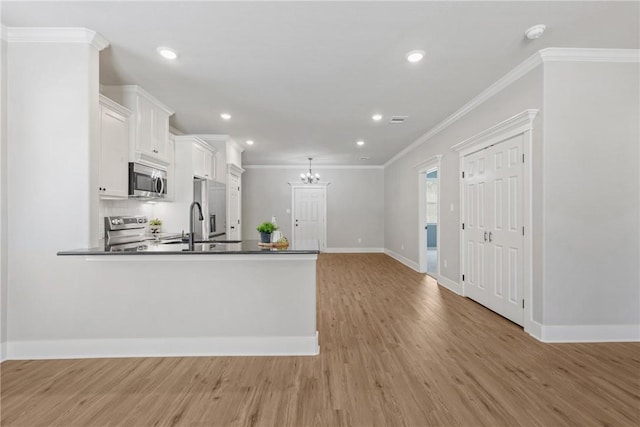 kitchen with ornamental molding, appliances with stainless steel finishes, light hardwood / wood-style floors, and white cabinets