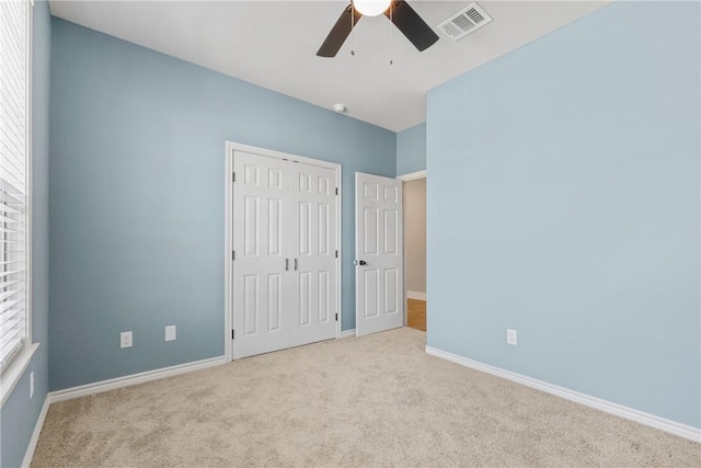 unfurnished bedroom with ceiling fan, light colored carpet, and a closet