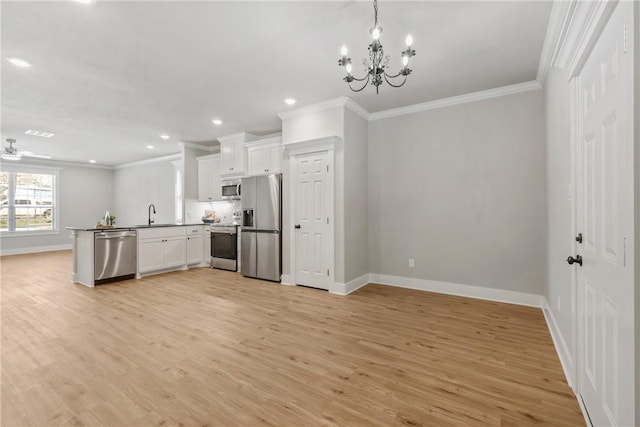 kitchen featuring appliances with stainless steel finishes, pendant lighting, white cabinetry, ornamental molding, and light hardwood / wood-style flooring