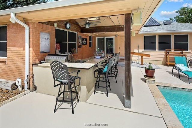 view of patio / terrace featuring a bar, ceiling fan, and exterior kitchen