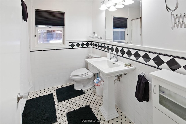 bathroom with tile patterned floors, sink, toilet, and tile walls