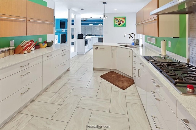 kitchen featuring sink, pendant lighting, extractor fan, stainless steel gas stovetop, and white cabinets