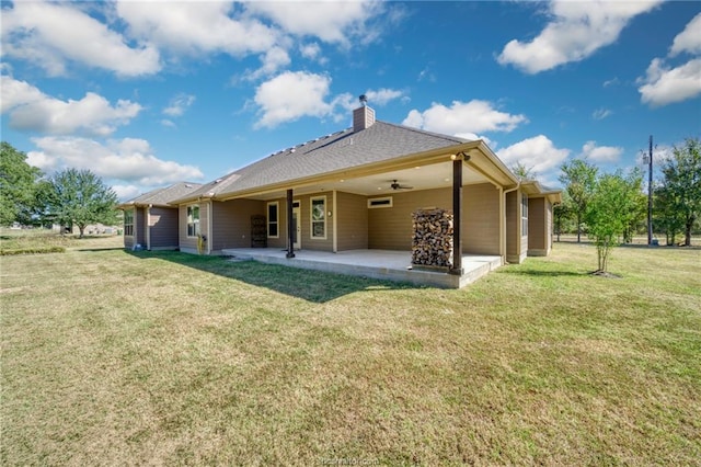 rear view of house with ceiling fan, a patio area, and a lawn