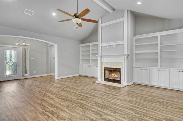 unfurnished living room featuring high vaulted ceiling, a high end fireplace, ceiling fan with notable chandelier, beam ceiling, and light hardwood / wood-style floors