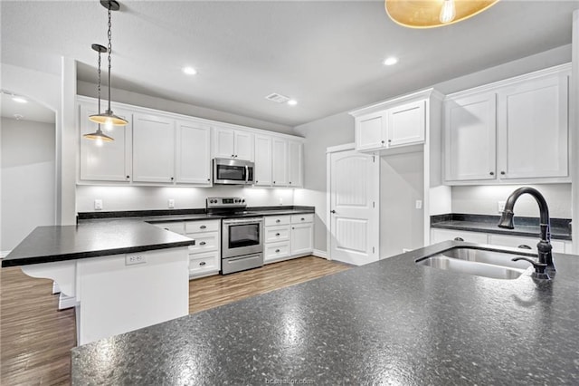 kitchen featuring white cabinets, stainless steel appliances, hanging light fixtures, and sink