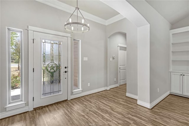 foyer entrance with a wealth of natural light, hardwood / wood-style floors, lofted ceiling, and ornamental molding