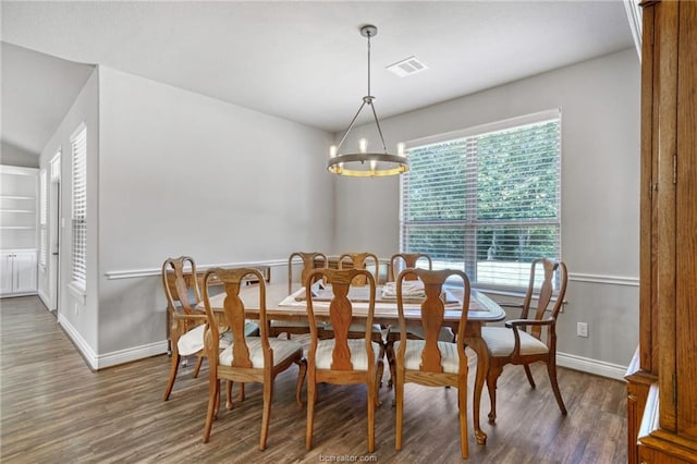 dining area featuring lofted ceiling, dark wood-type flooring, and a notable chandelier