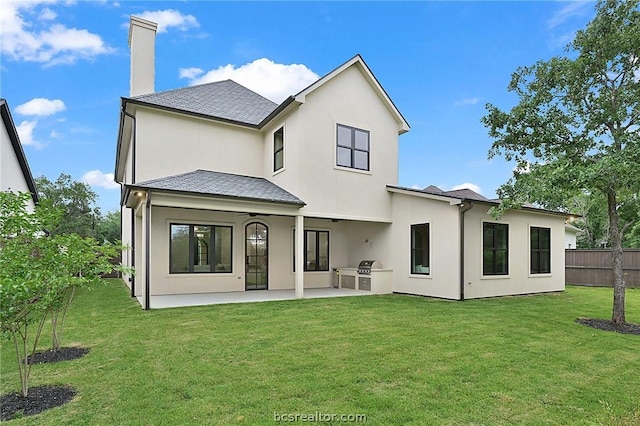 rear view of property featuring area for grilling, a patio area, and a lawn