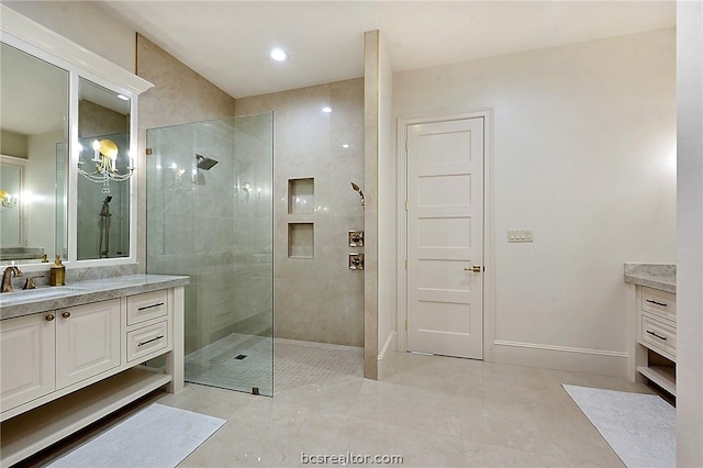 bathroom featuring an inviting chandelier, vanity, and tiled shower