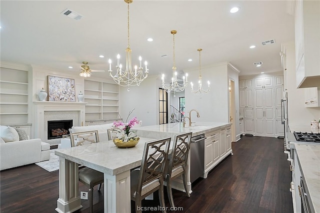 kitchen with a breakfast bar, dark wood-type flooring, sink, decorative light fixtures, and white cabinetry