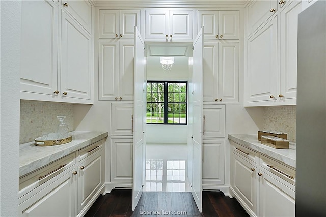 kitchen with backsplash, white cabinetry, dark wood-type flooring, and light stone counters