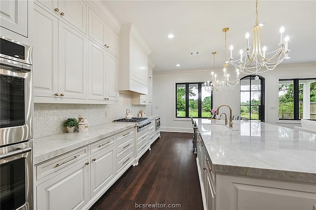 kitchen with dark wood-type flooring, white cabinets, sink, light stone countertops, and a large island