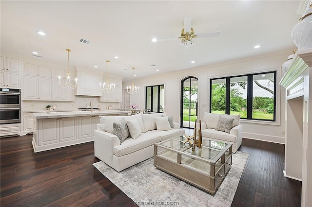 living room featuring crown molding, sink, ceiling fan with notable chandelier, and dark hardwood / wood-style floors