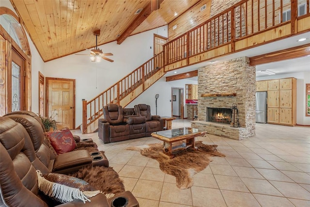 living room featuring light tile patterned floors, beam ceiling, high vaulted ceiling, a stone fireplace, and wooden ceiling