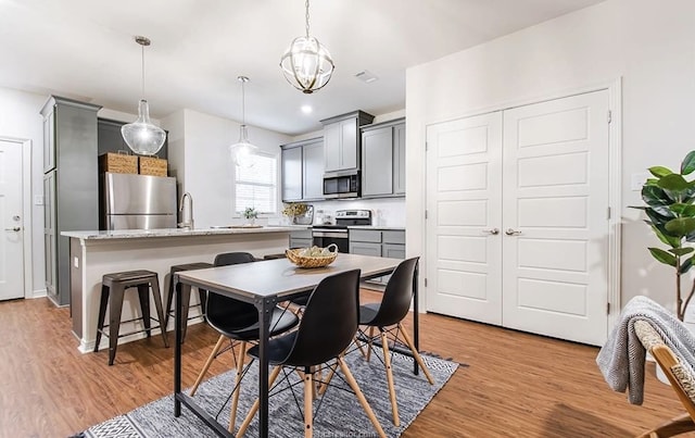 dining area featuring light hardwood / wood-style floors, a notable chandelier, and sink