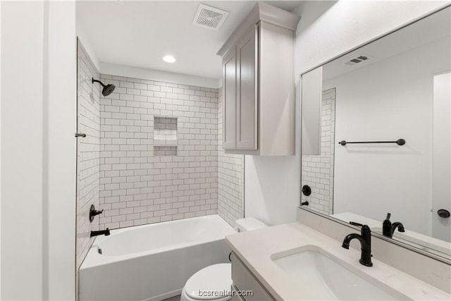 full bathroom featuring tiled shower / bath, vanity, and toilet