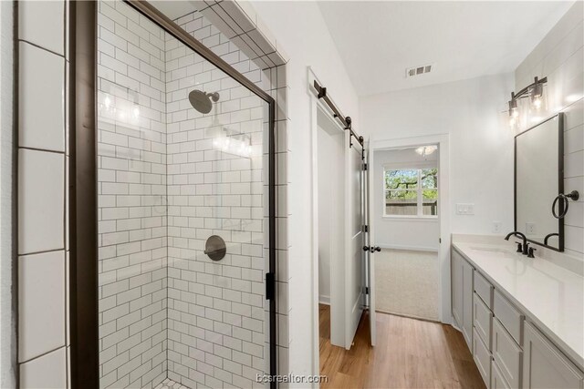 bathroom featuring hardwood / wood-style floors, vanity, and a shower with door