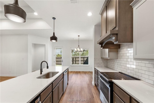 kitchen featuring appliances with stainless steel finishes, light hardwood / wood-style floors, pendant lighting, and sink