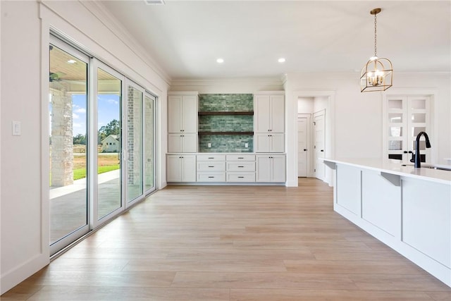 kitchen with sink, a chandelier, light hardwood / wood-style floors, white cabinetry, and hanging light fixtures