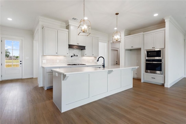 kitchen with hardwood / wood-style flooring, a center island with sink, white cabinetry, and stainless steel appliances