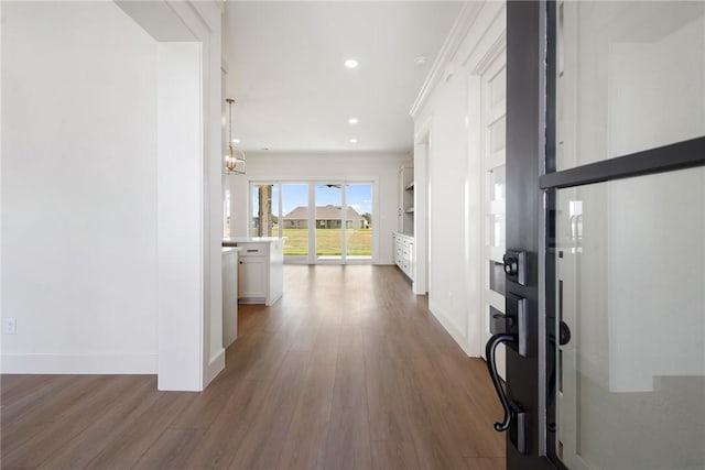 hallway with dark hardwood / wood-style flooring, an inviting chandelier, and crown molding