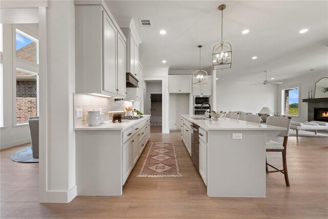 7800 Mathis Creek Dr, Bryan, TX 77808 - kitchen featuring a warm lit fireplace, appliances with stainless steel finishes, a sink, a kitchen breakfast bar, and open floor plan